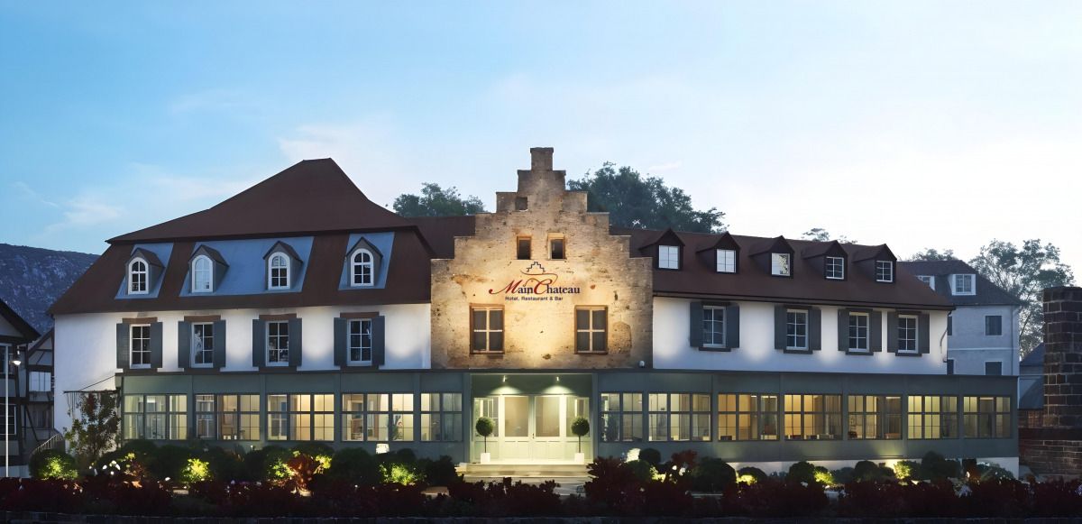 Außenansicht des Hotels mit beleuchtetem Eingangsbereich und vielen Fenstern.